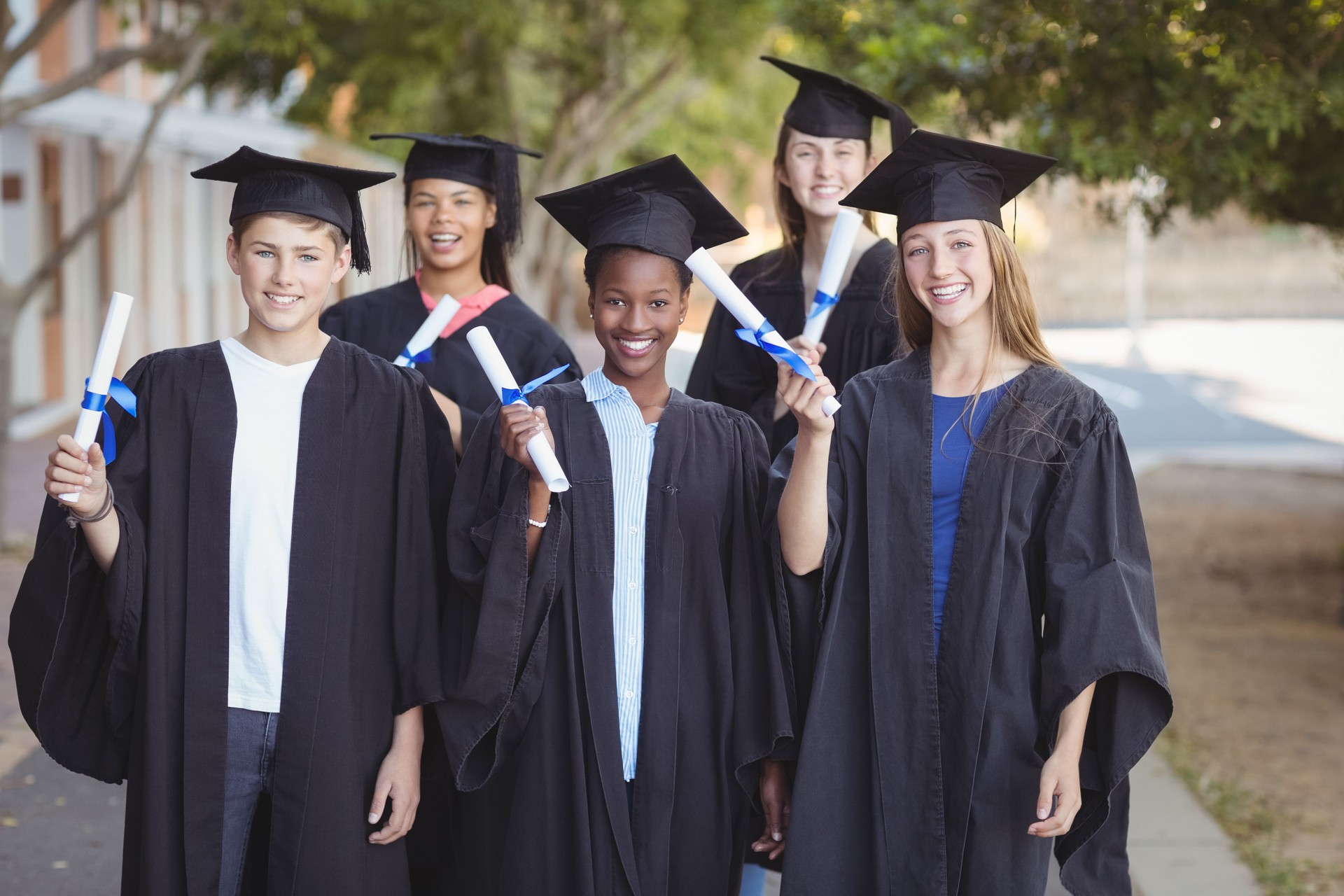 Portrait de l’école d’études supérieures des enfants debout avec défilement de degré dans le campus